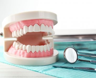 White,Teeth,And,Dental,Instruments,On,Table,Background