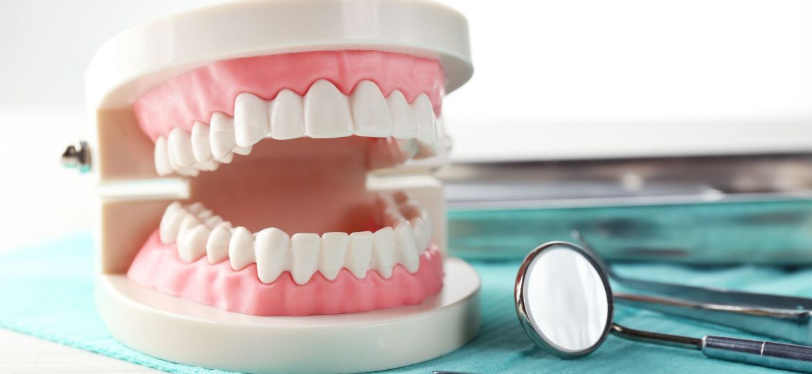 White,Teeth,And,Dental,Instruments,On,Table,Background